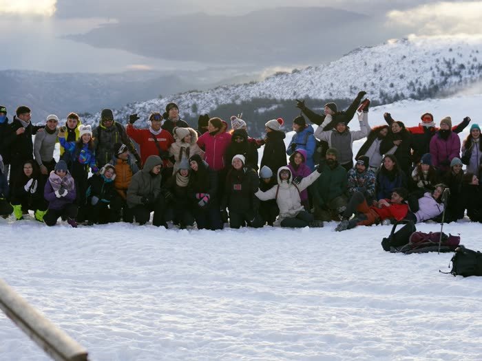 Decenas de personas con los brazos en alto en la cima nevada