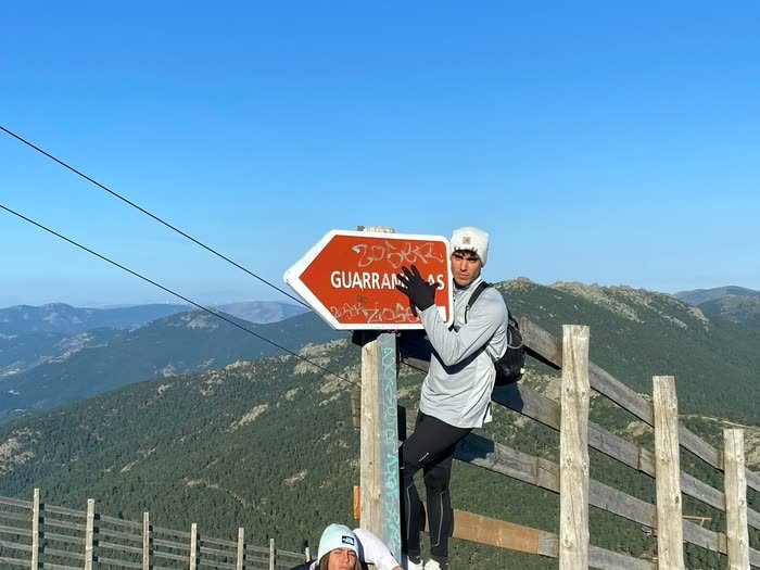 Dos personas junto al cartel de la cima, una subida a lo alto