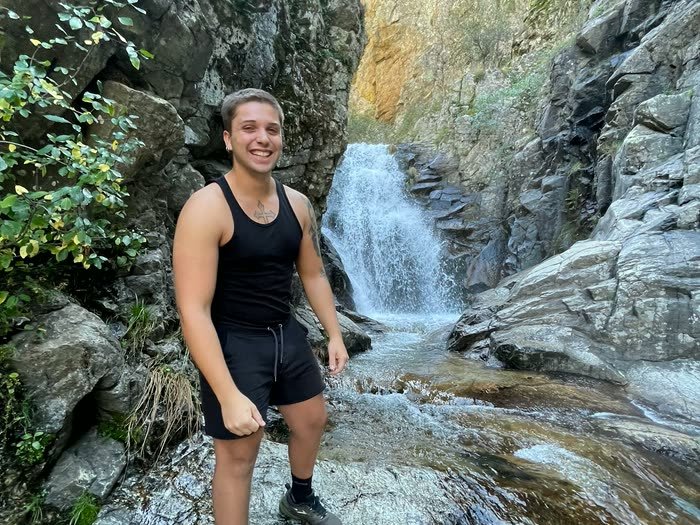 Un chico en las rocas frente a la cascada