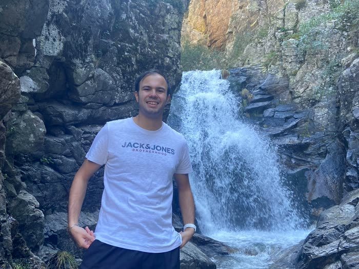 Otro de pie ante la cascada, sonriendo