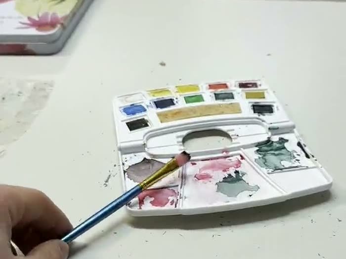 Una caja de acuarelas abierta sobre la mesa larga