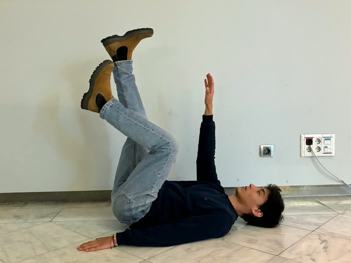 Alguien tumbado en el suelo con las piernas en la pared, haciendo de modelo