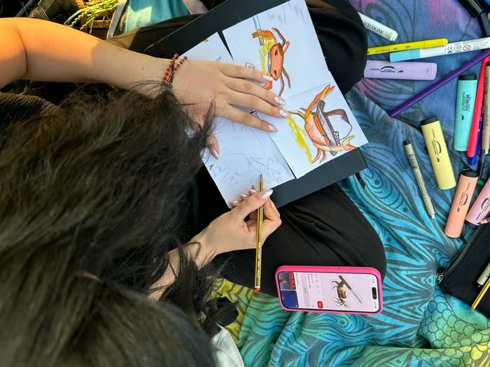 Un cuaderno con un dibujo a medias y los colores alrededor