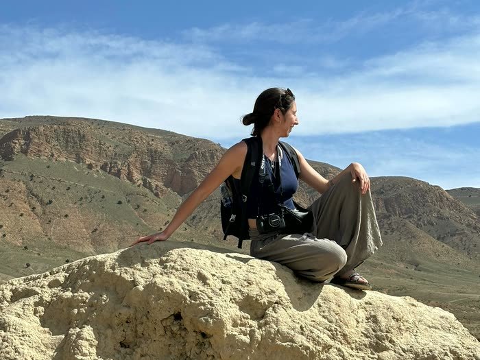 Sentada en una roca frente a las montañas del Atlas