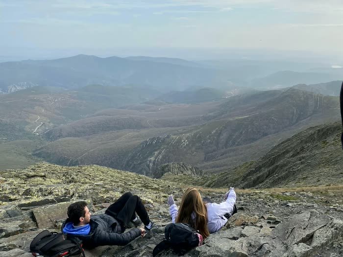 Gente tumbada en las rocas mirando el valle