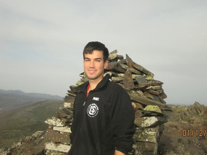 Un chico junto al hito de piedras de la cima