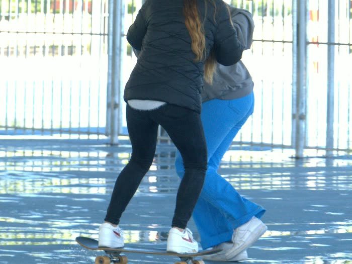 Dos chicas patinando de la mano en una pista