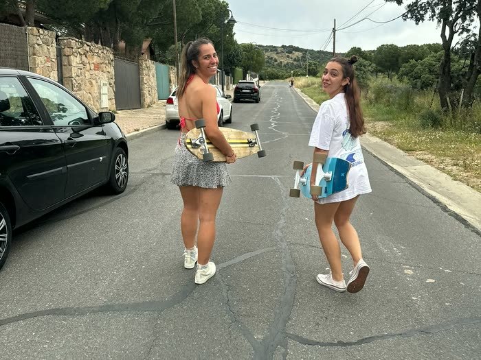 Dos chicas patinando por una carretera
