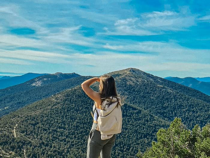 Una chica mirando las montañas desde la cumbre