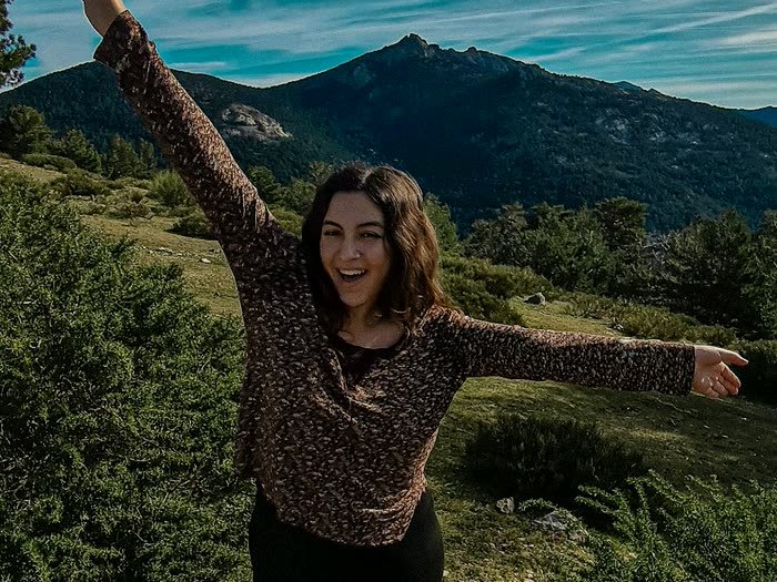 Una chica con el brazo en alto y la montaña detrás