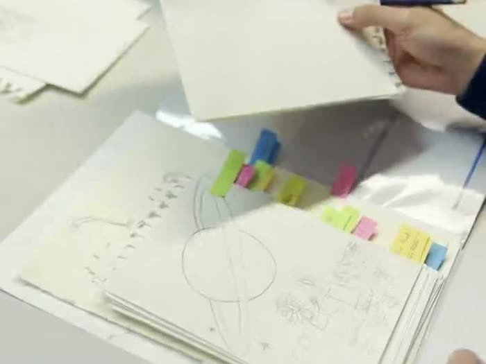 Manos dibujando en un cuaderno lleno de pósits