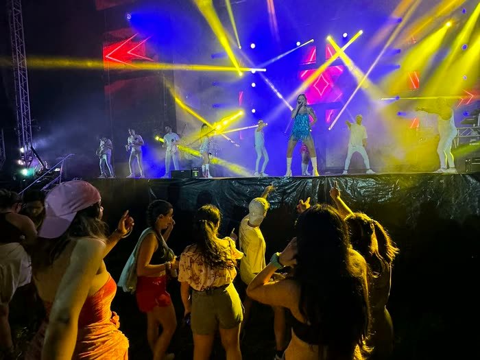 Un concierto con luces amarillas y el público bailando
