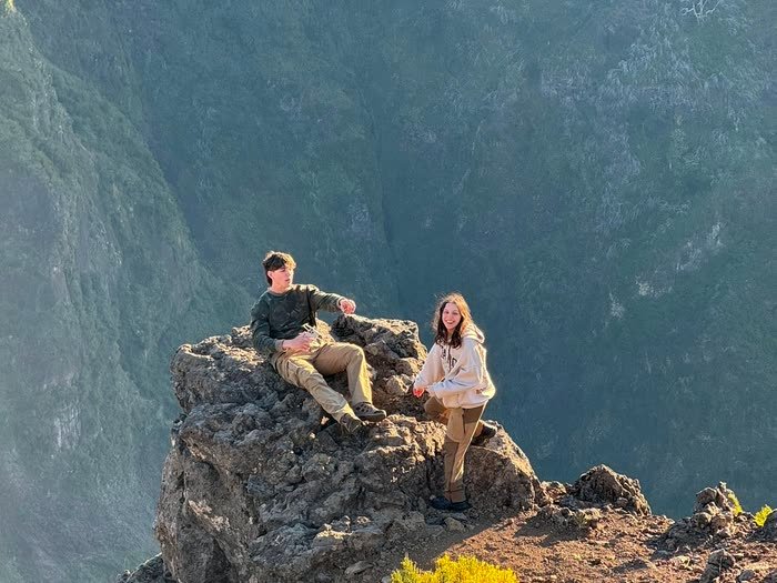 Dos personas en lo alto de una roca, por encima de las nubes