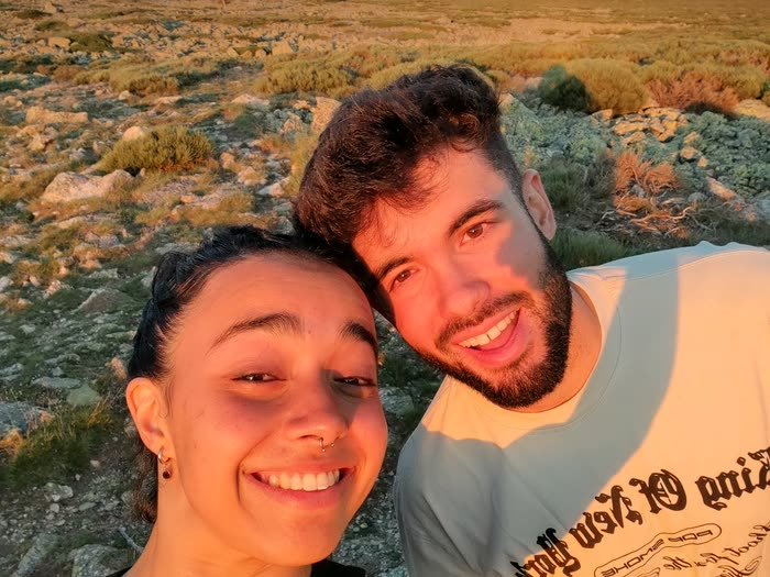 Un selfi de dos amigos sonriendo en la montaña