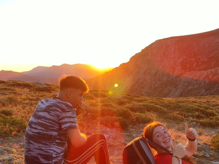Dos sentados en la ladera con el sol poniéndose