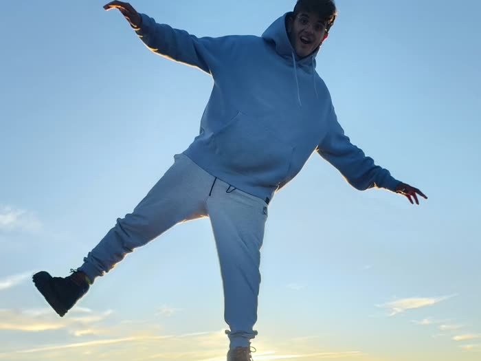 Un chico haciendo equilibrio sobre un poste al atardecer