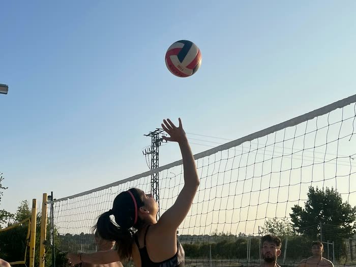 Una chica sacando en la pista de vóley playa